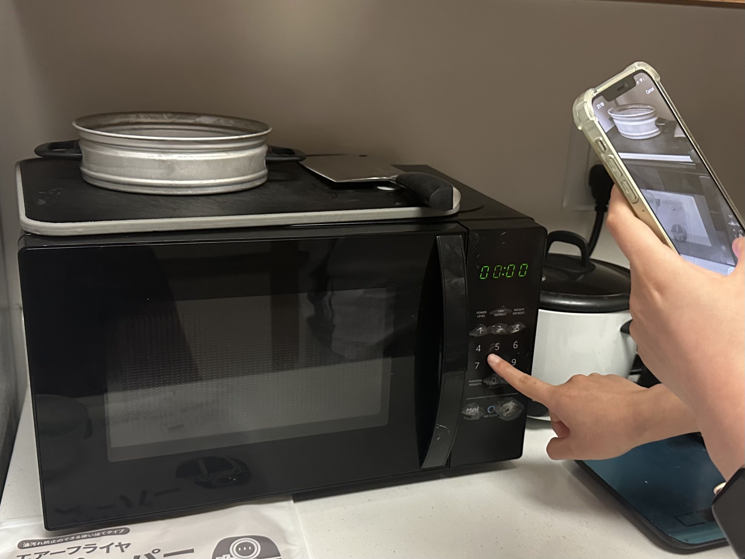 Many flat interfaces are inaccessible to blind and visually-impaired people. This photo shows a person using the microwave panel with the help of our Vizlens app.